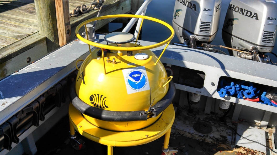 Photo of a yellow water level buoy with a NOAA label attached sitting in a boat ready to be launched.